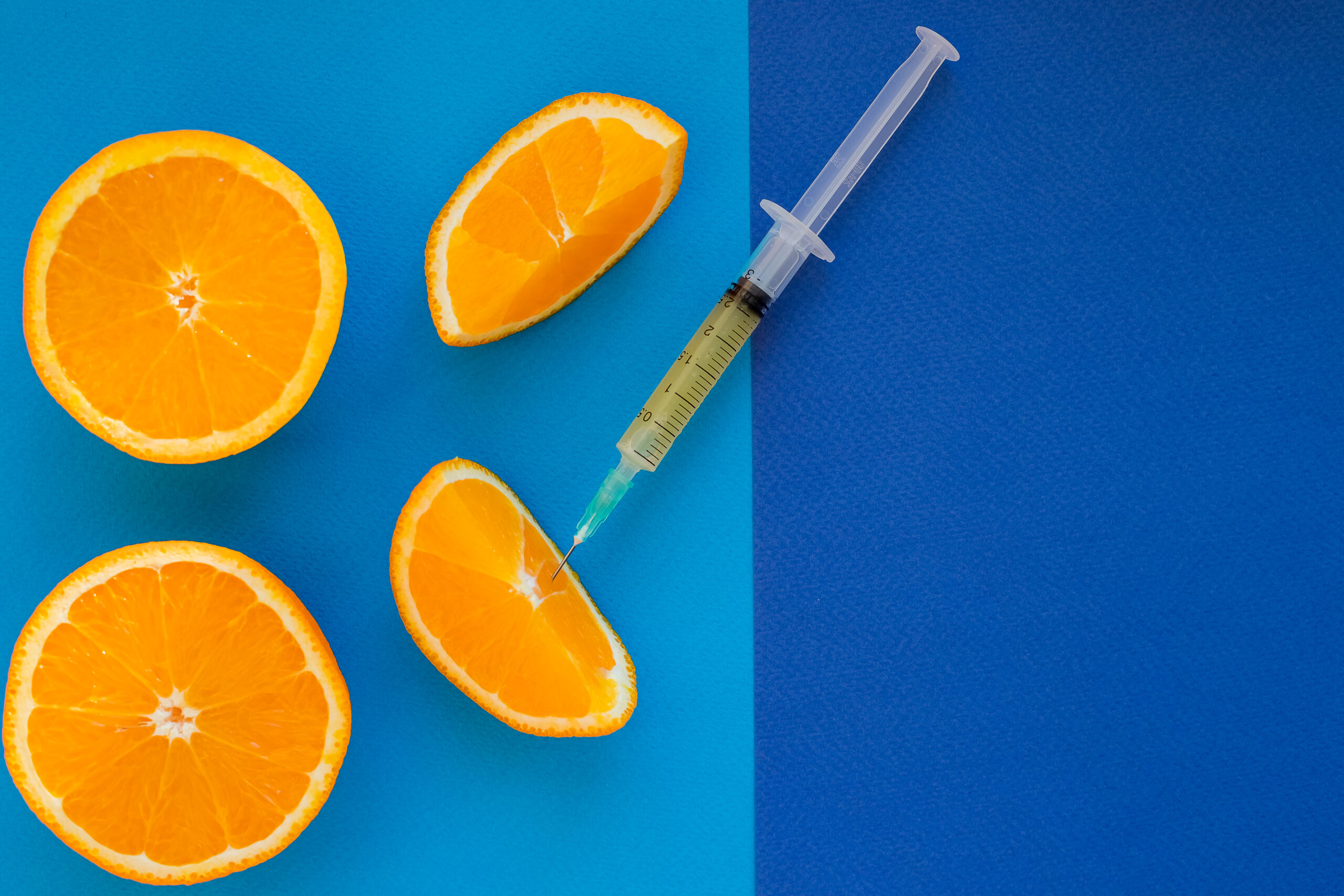 Vitamin C , syringe on fresh juicy orange fruit slides. Conceptual image of mineral,vitamin,medical supplement and health. Selective focus .Copy space.Genetic modification concept
